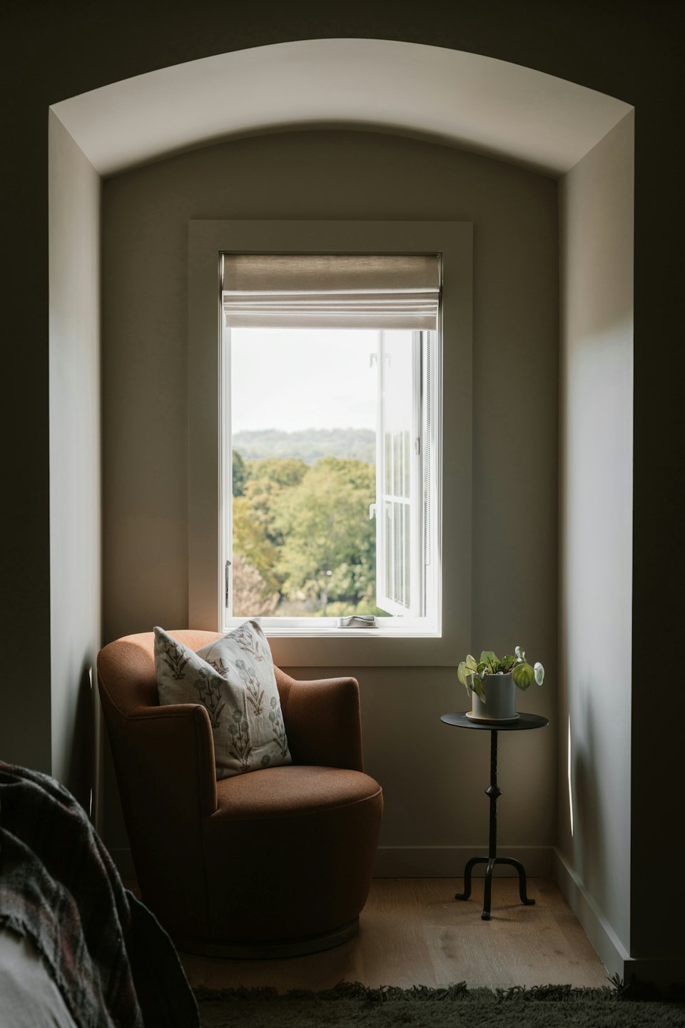 Armchair by window with trees and hills beyond.